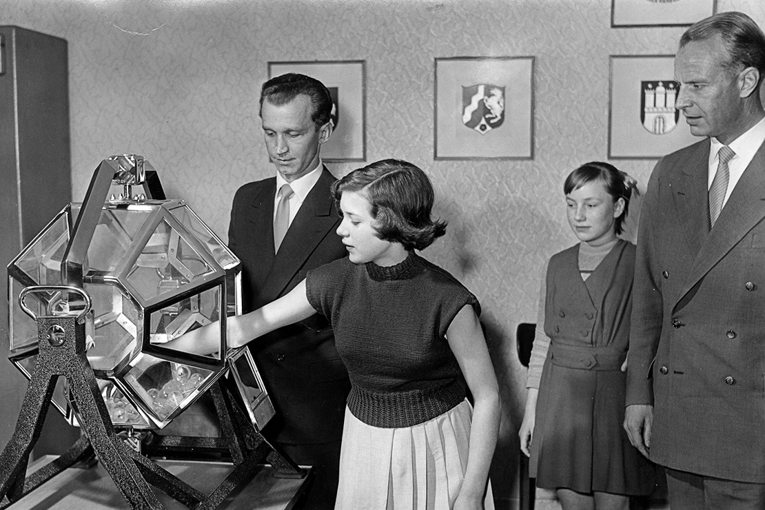 Lotto-Ziehung als schwarz-weiß Bild: Frau greift nach Lottokugel.