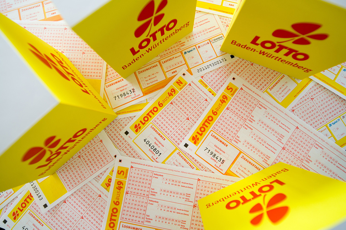 Viele Lottoscheine liegen aufeinander und vier Aufsteller zeigen Lotto BW-Logo.